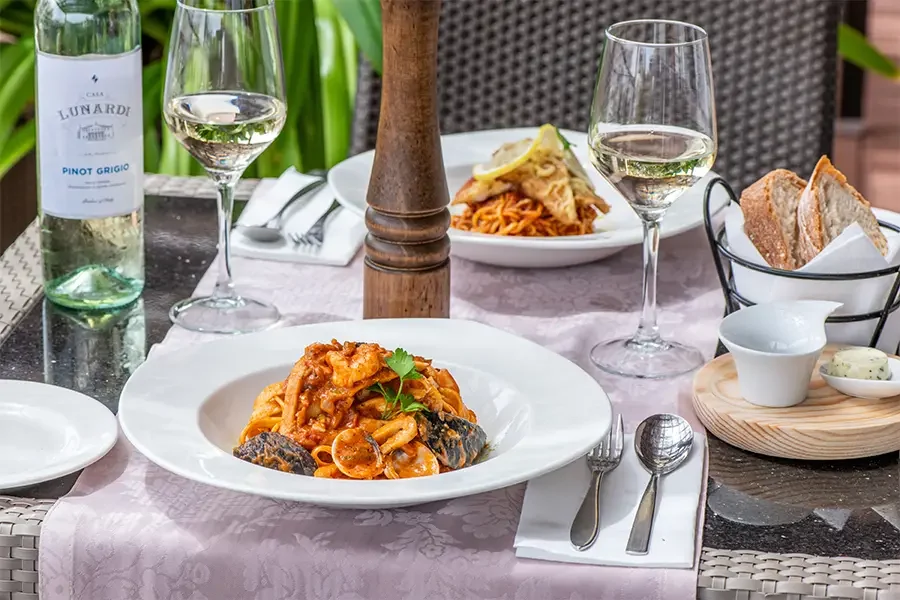 Pasta y vino pinot grigio servidos en una mesa