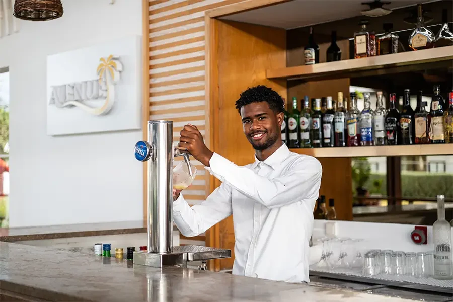 Personne se tenant au comptoir d'un bar servant de la bière à la pression.