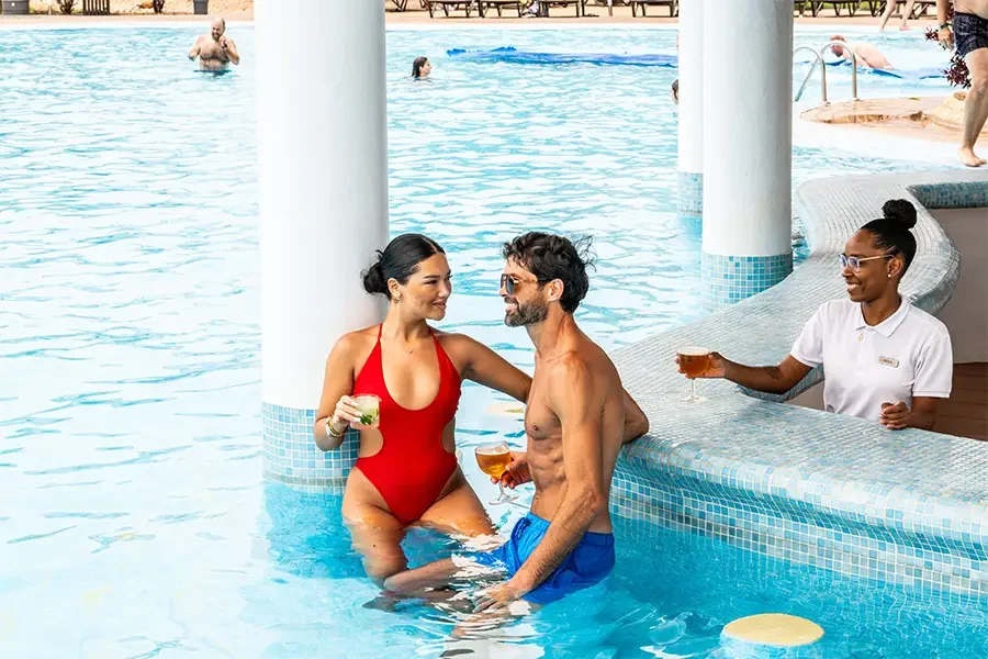 Pareja en una piscina disfrutando de bebidas en un swim-up bar